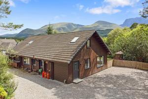 a wooden cabin with mountains in the background at Finest Retreats - The Logs in Fort William