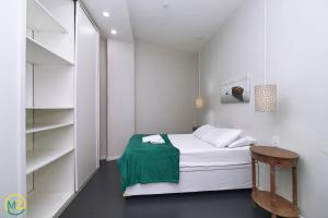 a small white bedroom with a bed and shelves at Moderno 2 quartos p/ 6 pessoas a 50m da praia in Rio de Janeiro
