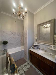 a bathroom with a tub and a sink and a chandelier at L’orangerie chambres d’hôtes in Motteville