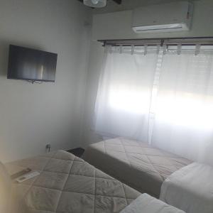 two beds in a room with a window and a tv at Departamento sierras Balcarce in Balcarce