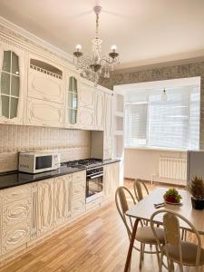 Una cocina con gabinetes blancos y una mesa con sillas. en ЖК Саулет Курылыс 5к1 70, en Aktobe 11 fotos más