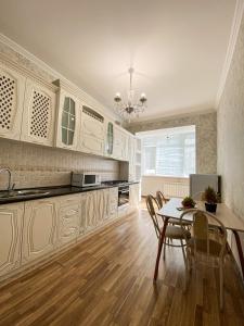 Una cocina con gabinetes blancos y una mesa y sillas. en ЖК Саулет Курылыс 5к1 70, en Aktobe
