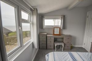 Schlafzimmer mit einem Bett, einem Schreibtisch und Fenstern in der Unterkunft Sealark in Bridport