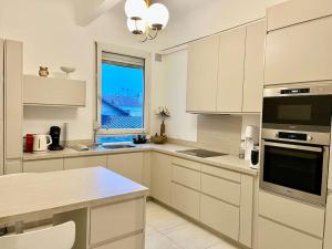 a kitchen with white cabinets and a large window at The Gallery - HyperCentre Reims in Reims