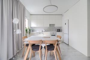 uma cozinha branca com mesa e cadeiras em Warta River Comfort Apartment em Poznań