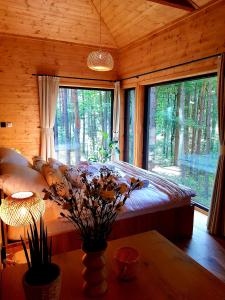 a bedroom with a bed and a large window at Tree Houses Olszanka in Puszcza Mariańska