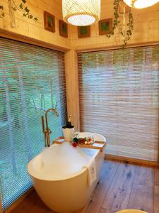 a bathroom with a tub and a large window at Tree Houses Olszanka in Puszcza Mariańska +53 photos