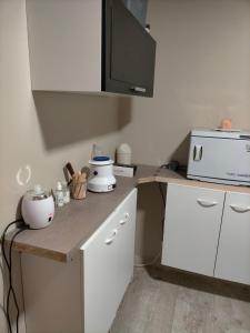 a kitchen with white cabinets and a counter with a microwave at Appartement tout confort in Guipry-Messac