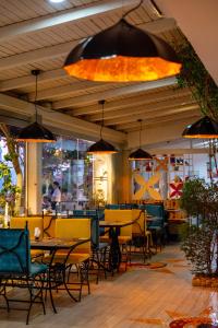 a restaurant with tables and chairs and a large light fixture at Bougainville Bay Hotel in Sarandë