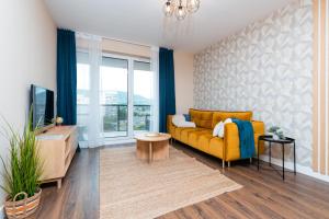 a living room with a yellow couch and a tv at WaterFront City Apartments by UrbanRent in Budapest