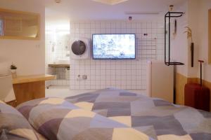 a bedroom with a bed and a tv on the wall at TGS Studio Hotel in Guangzhou