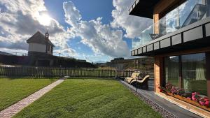 a house with a yard with a lighthouse in the background at Albergo Vezzana in Passo Rolle