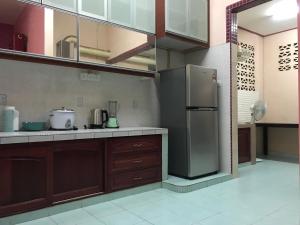 uma cozinha com armários de madeira e um frigorífico de aço inoxidável em SAHMURA HOMESTAY 1 at GONG BADAK em Kuala Terengganu