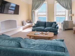a living room with two blue couches and a table at 123 On The Sea in Weymouth