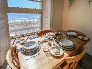 a wooden table with plates and dishes on it with a view of the beach at 123 On The Sea in Weymouth