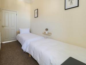 two beds in a room with white walls at 123 On The Sea in Weymouth