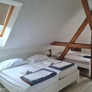 2 łóżka pojedyncze w pokoju z drewnianymi belkami stropowymi w obiekcie AZUR ROOMS LJUBLJANA w Lublanie