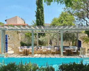 a pergola over a swimming pool with a table and chairs at Apokryfo Traditional Guesthouse in Lofou