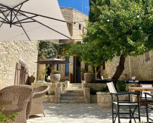 a patio with tables and chairs and an umbrella at Apokryfo Traditional Guesthouse in Lofou