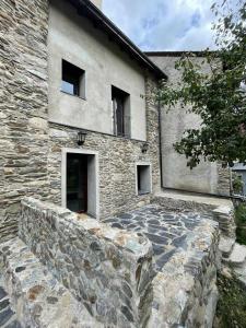 ein Steingebäude mit einer Steinmauer davor in der Unterkunft CASA CON ENCANTO ESTERRI in Esterri d'Àneu