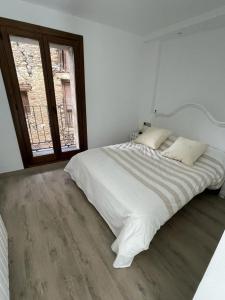 ein weißes Schlafzimmer mit einem großen Bett und einem Fenster in der Unterkunft CASA CON ENCANTO ESTERRI in Esterri d'Àneu