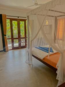 希卡杜瓦的住宿－Easy Living，一间卧室配有一张带蚊帐的床