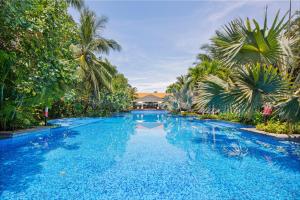 a large blue swimming pool with palm trees at Abogo Resort Villa Beach Premium in Da Nang