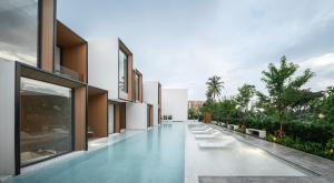an external view of a building with white chairs and trees at Riva Vista Riverfront Resort Chiang Rai in Chiang Rai