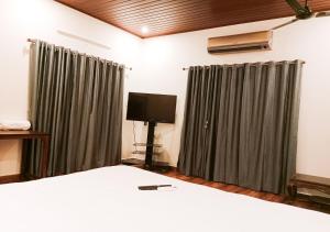 a bedroom with a bed and a flat screen tv at Vaiga Homes - Vembanadu Lakeview Retreat in Cochin