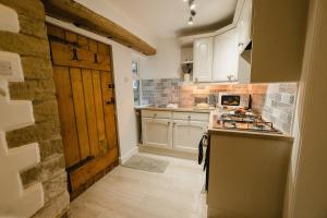 a kitchen with white cabinets and a wooden door at Swan House in Huddersfield