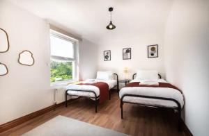 two beds in a room with white walls and a window at Metropolitan - 203 Millbrook Road East in Southampton