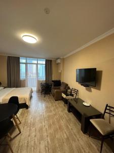 a hotel room with a bed and a couch and a tv at Pirosmani Mini Hotel in Batumi