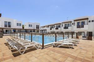 a row of chaise lounge chairs sitting on a patio at La Malvarrosa in Puerto Calero