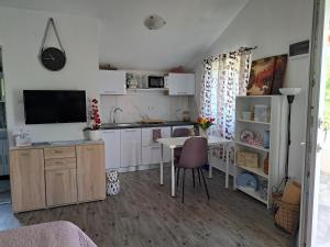 una cucina con armadi bianchi, tavolo e televisore di Apartmani DBS a Vir (Puntadura)