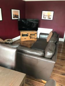 a living room with a leather couch and a flat screen tv at Prestwick Flat Central Location in Prestwick