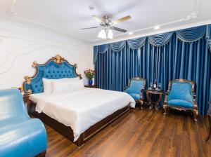 a bedroom with a bed and two blue chairs at Hoang Gia Hotel Ha Noi Capital in Hanoi