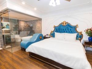 a bedroom with a king sized bed and a blue chair at Hoàng Gia Hotel Hà Nội in Hanoi