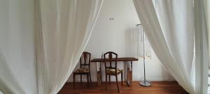 a table and two chairs in a room with curtains at La Commenda di Picciano - Country House in Matera