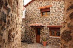 a stone building with a door and two windows at Ca abuela María in Solana de ávila