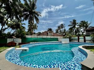 a swimming pool in a yard with palm trees at Red Sea Beach Resort in Anjuna