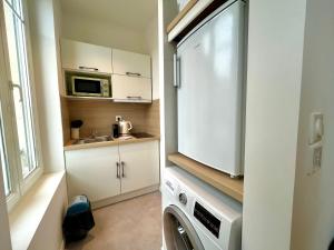 eine Küche mit einer Waschmaschine und einer Mikrowelle in der Unterkunft Suite Clovis 5 in Reims