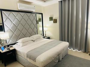 ein Schlafzimmer mit einem großen Bett mit einem großen Kopfteil in der Unterkunft كرم النخلة للشقق المخدومة in Riad