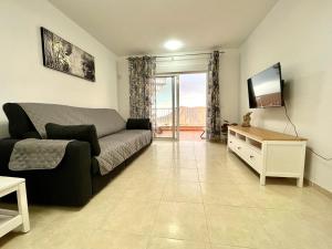 a living room with a couch and a flat screen tv at One bedroom apartment ZEN with great view, pool, WiFi in Chayofa