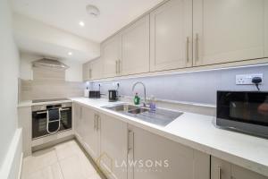 a kitchen with white cabinets and a sink at Modern Living by Lawsons in Windsor
