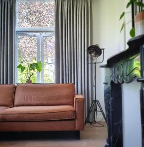 een woonkamer met een bank voor een raam bij Appartement 'Wij en de Zande' in Kamperveen