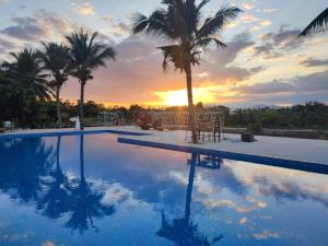 a swimming pool with palm trees and a sunset at Home at 9 in Ban Klang (4)