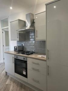 una cucina con armadi bianchi e piano cottura di Lighthouse View - Lovely 3 bed 1st floor apartment a Fleetwood