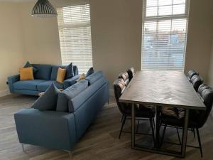 a living room with a blue couch and a table at Lighthouse View - Lovely 3 bed 1st floor apartment in Fleetwood