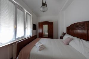 um quarto com uma cama com uma cabeceira em madeira e janelas em Maison Cècile Appartamento in villa. Host Marianna em Agliè