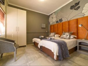 a bedroom with two beds and a wall with flowers at Leeuwenzee Guesthouse in Cape Town
